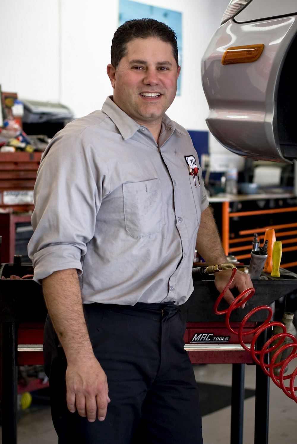 man in gray button up shirt and black pants standing near black and red power tool