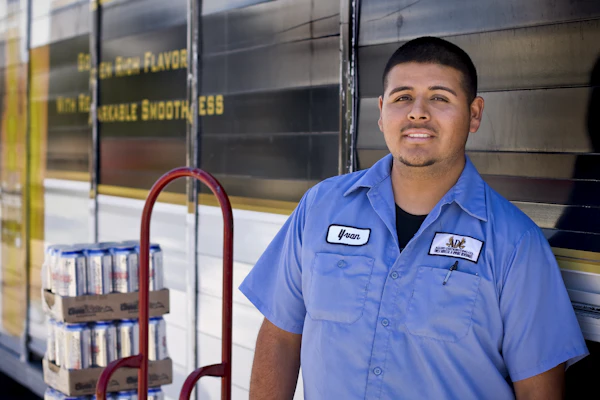 A smiling worker in a blue work shirt in a warehouse
