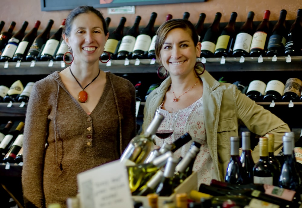 woman in brown jacket standing beside woman in white shirt