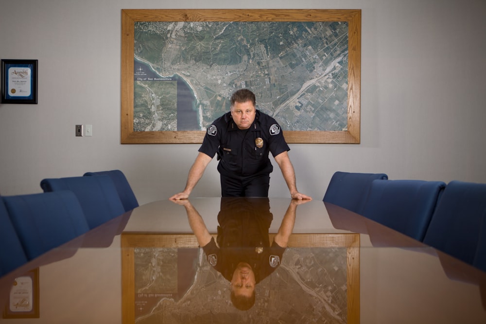 man in black t-shirt standing beside brown wooden table