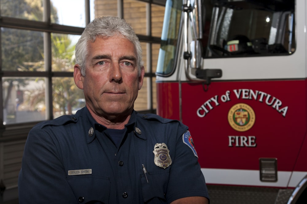 man in blue button up shirt standing beside red and white truck during daytime