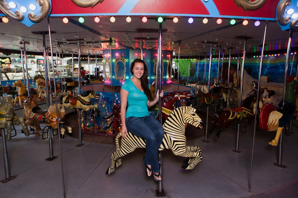 woman in blue shirt and white and black striped pants sitting on carousel