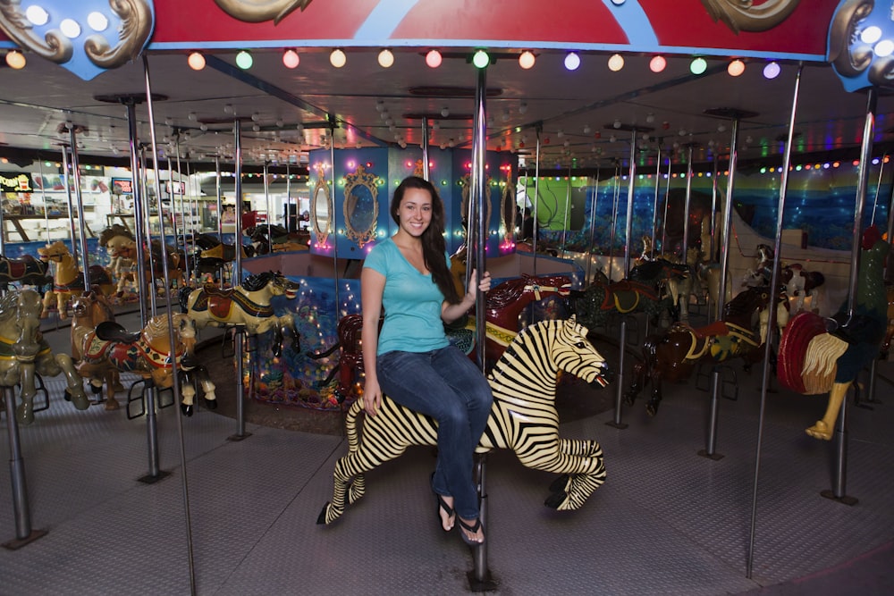 Femme en chemise bleue et pantalon rayé blanc et noir assise sur le carrousel