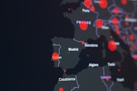 A dark-themed map highlighting parts of Europe and North Africa with red circles indicating specific locations. Major cities like Lisbon, Madrid, and Casablanca are labeled. The circles suggest a possible data visualization, such as population density or COVID-19 cases.