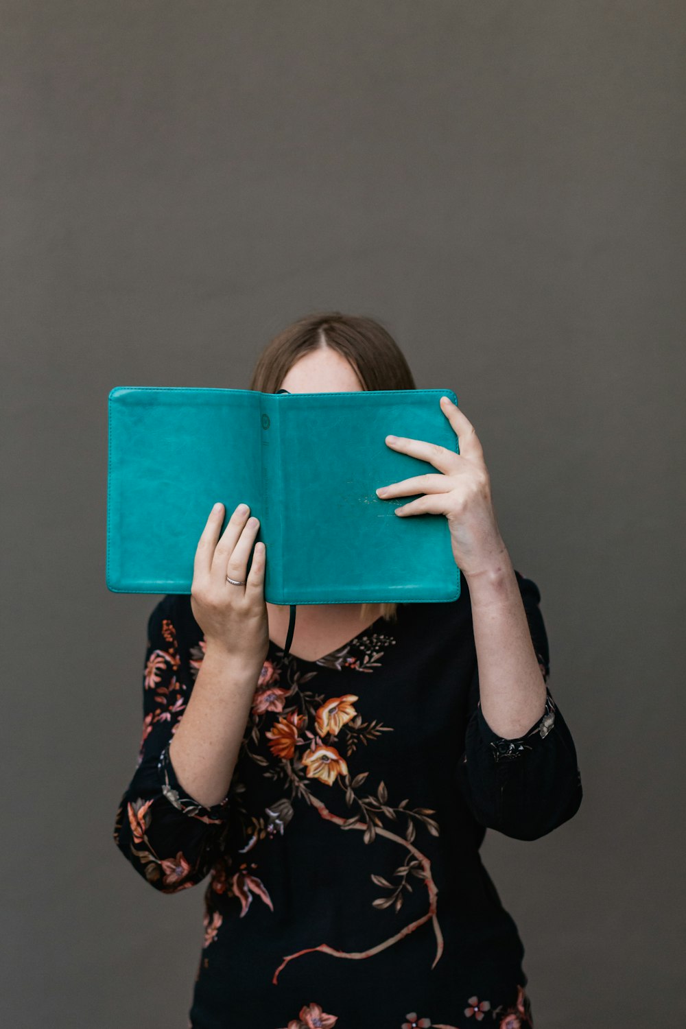 woman in black and white floral long sleeve shirt holding blue tablet computer