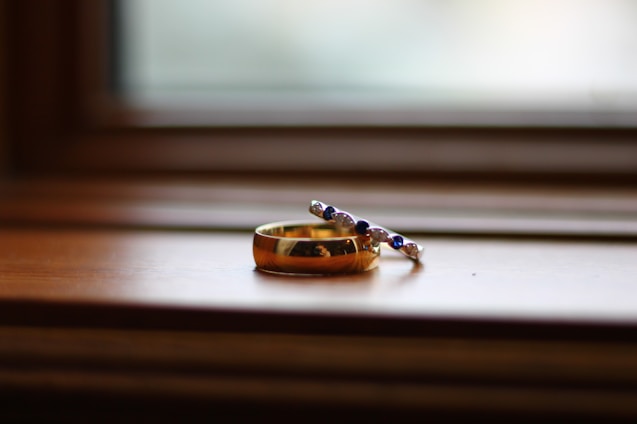 Close-up of a minimalist silver ring and gold necklace displayed on a soft fabric background.