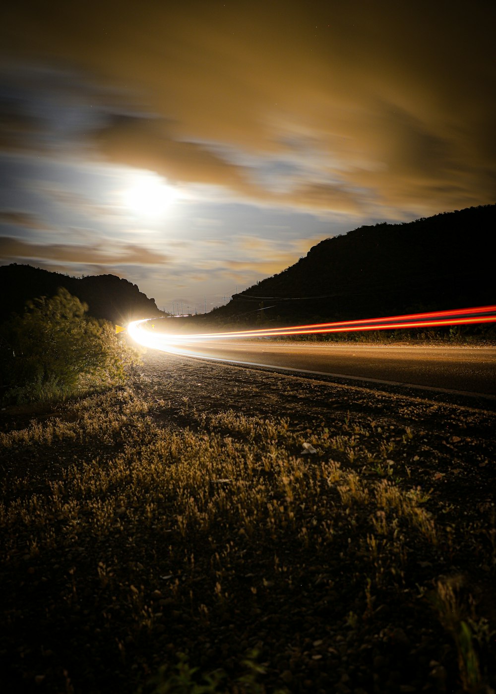 green grass field near road during sunset