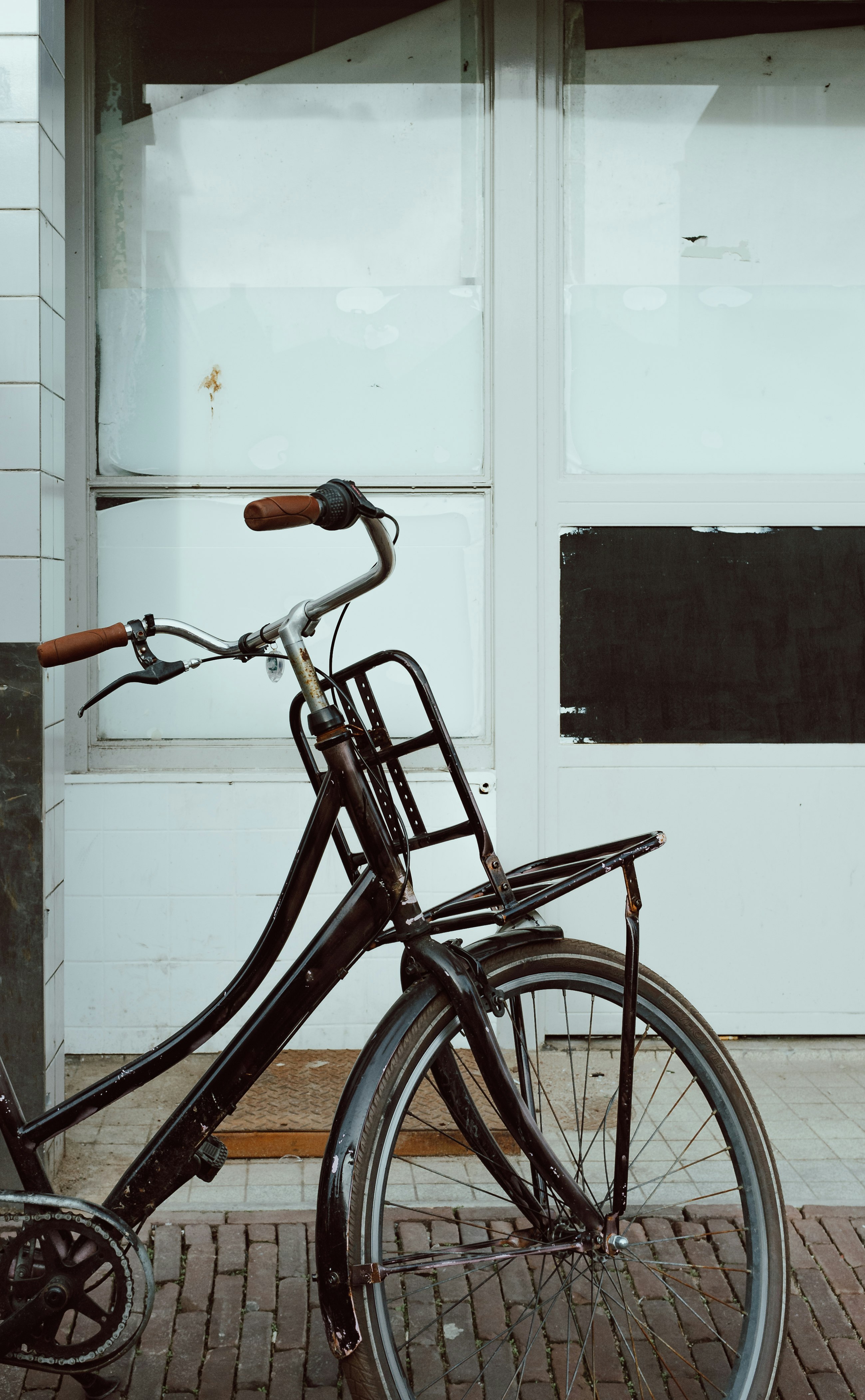 brown city bike parked beside white wooden door