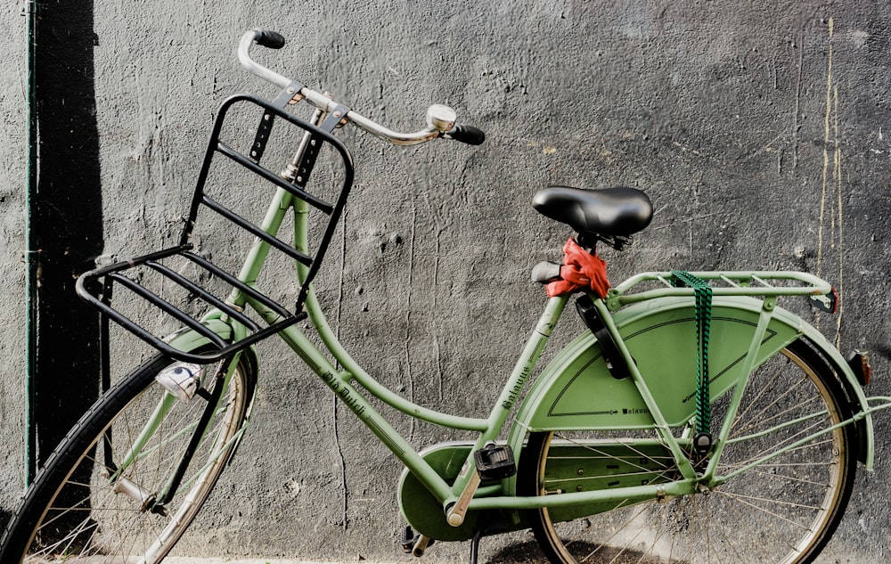 Bicicleta de ciudad verde apoyada en la pared