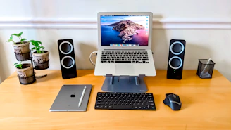 A sleek, modern workspace featuring a laptop, wireless router, and stylish speakers arranged neatly.