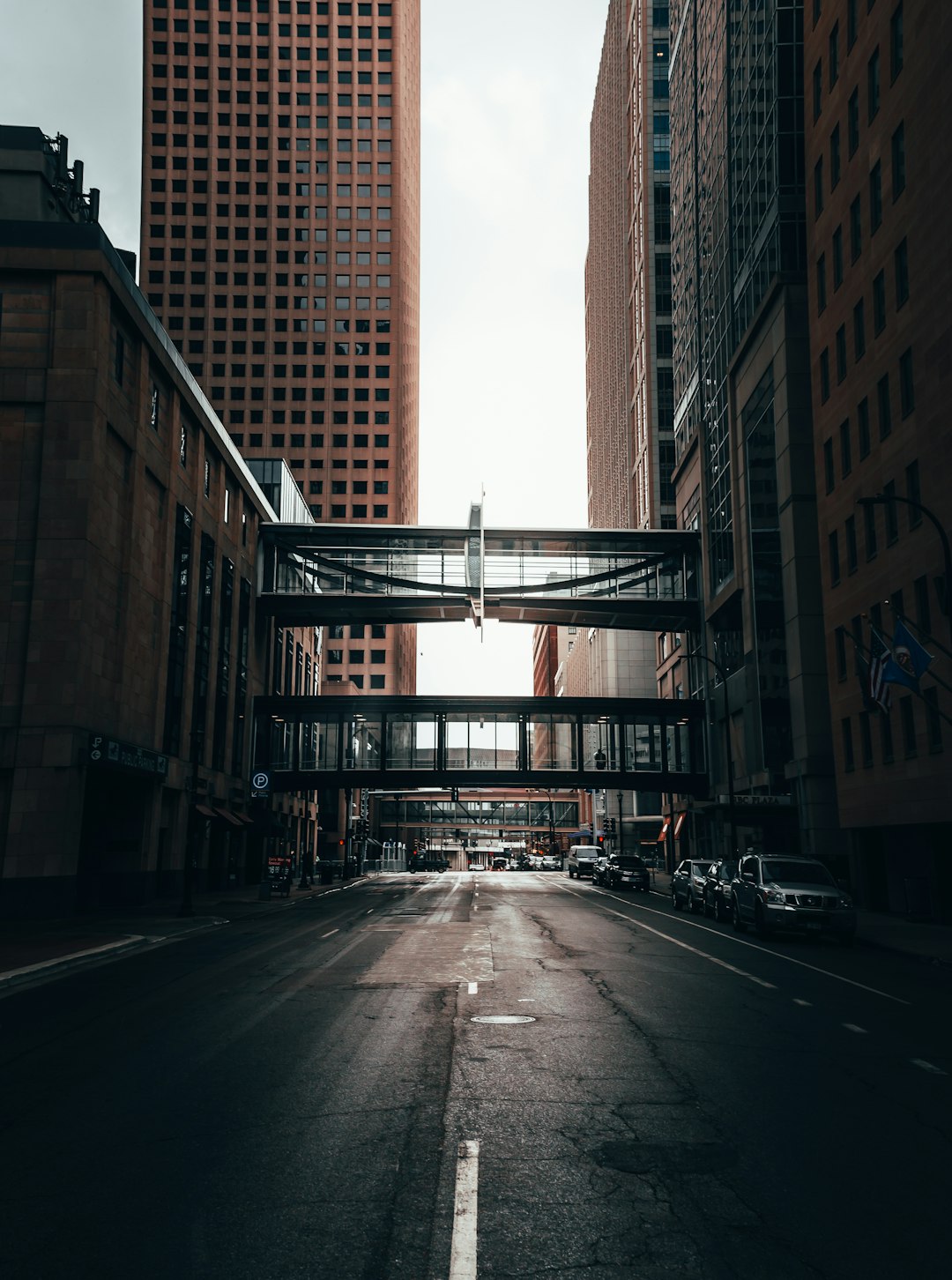 cars parked on side of the road in between high rise buildings during daytime