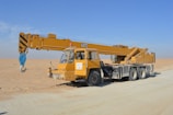 yellow and black excavator on white sand during daytime
