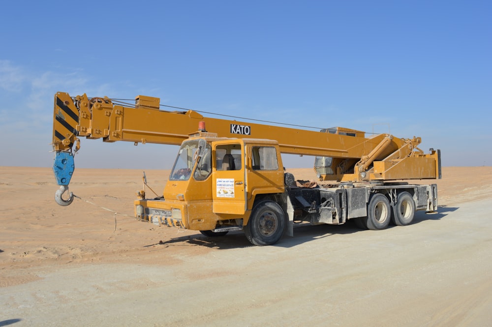 yellow and black excavator on white sand during daytime