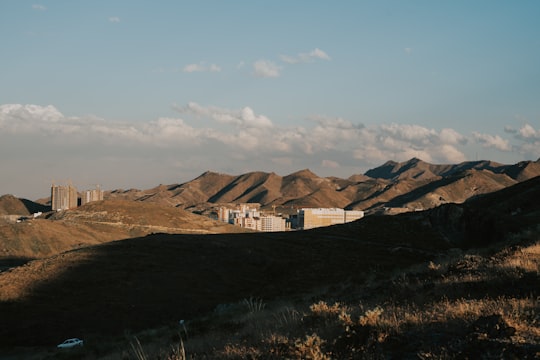 brown and white concrete building near brown mountain under blue sky during daytime in Mashhad Iran