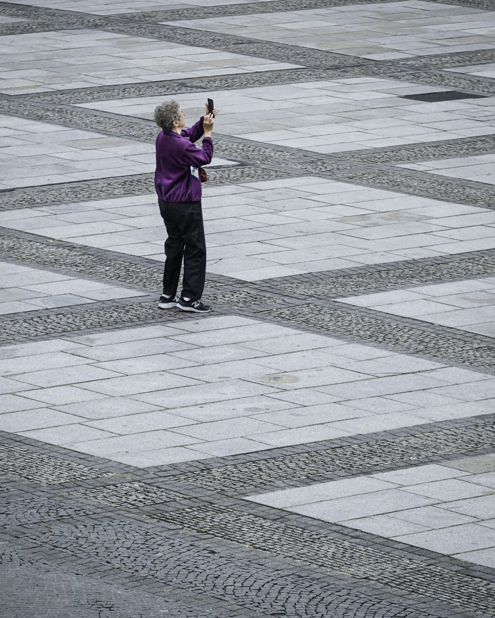 woman in purple jacket and black pants standing on gray concrete floor during daytime