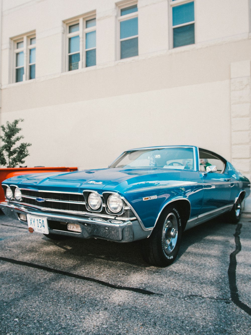 blue chevrolet camaro parked near white concrete building during daytime