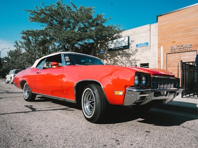 orange muscle car parked near brown concrete building during daytime pleasant zoom background