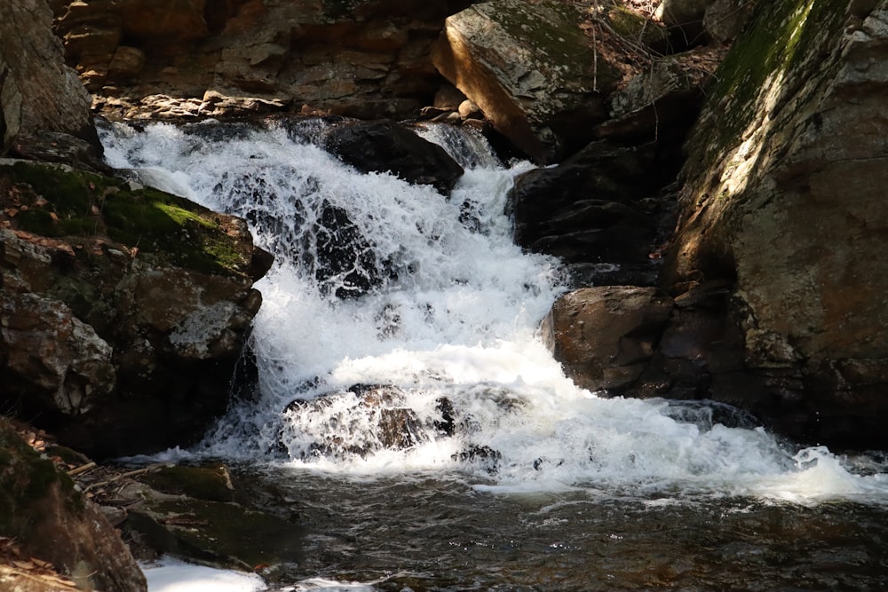 water falls on rocky shore during daytime