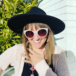 Close-up of a Black woman smiling brightly, wearing pastel green accessories in lively city surroundings.