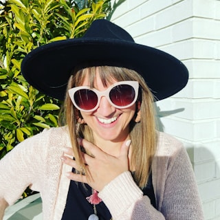 A woman in a flowing dress paired with bold accessories, smiling under the sun with trendy sunglasses