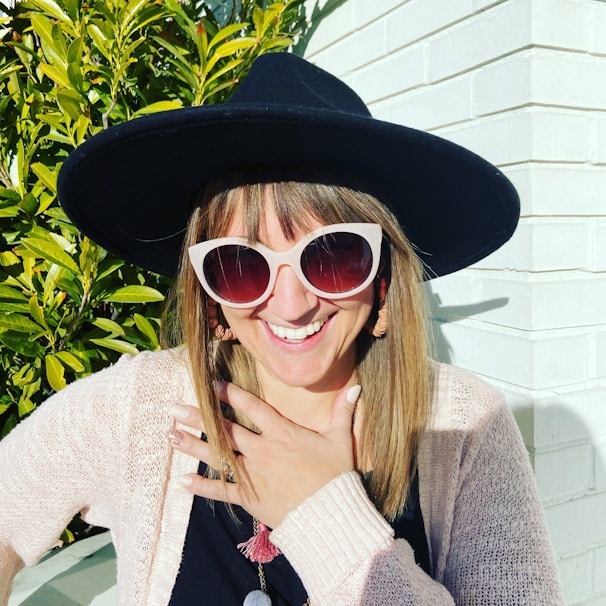 A woman in a flowing dress paired with bold accessories, smiling under the sun with trendy sunglasses