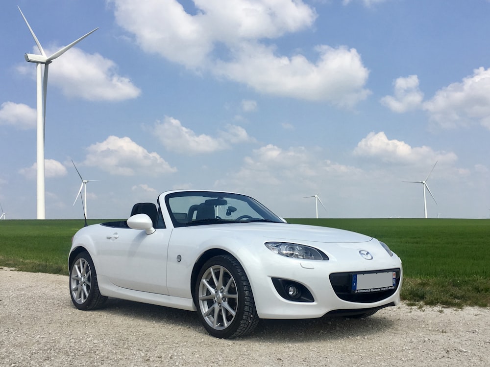 Porsche 911 blanche sur un champ d’herbe verte sous un ciel bleu pendant la journée