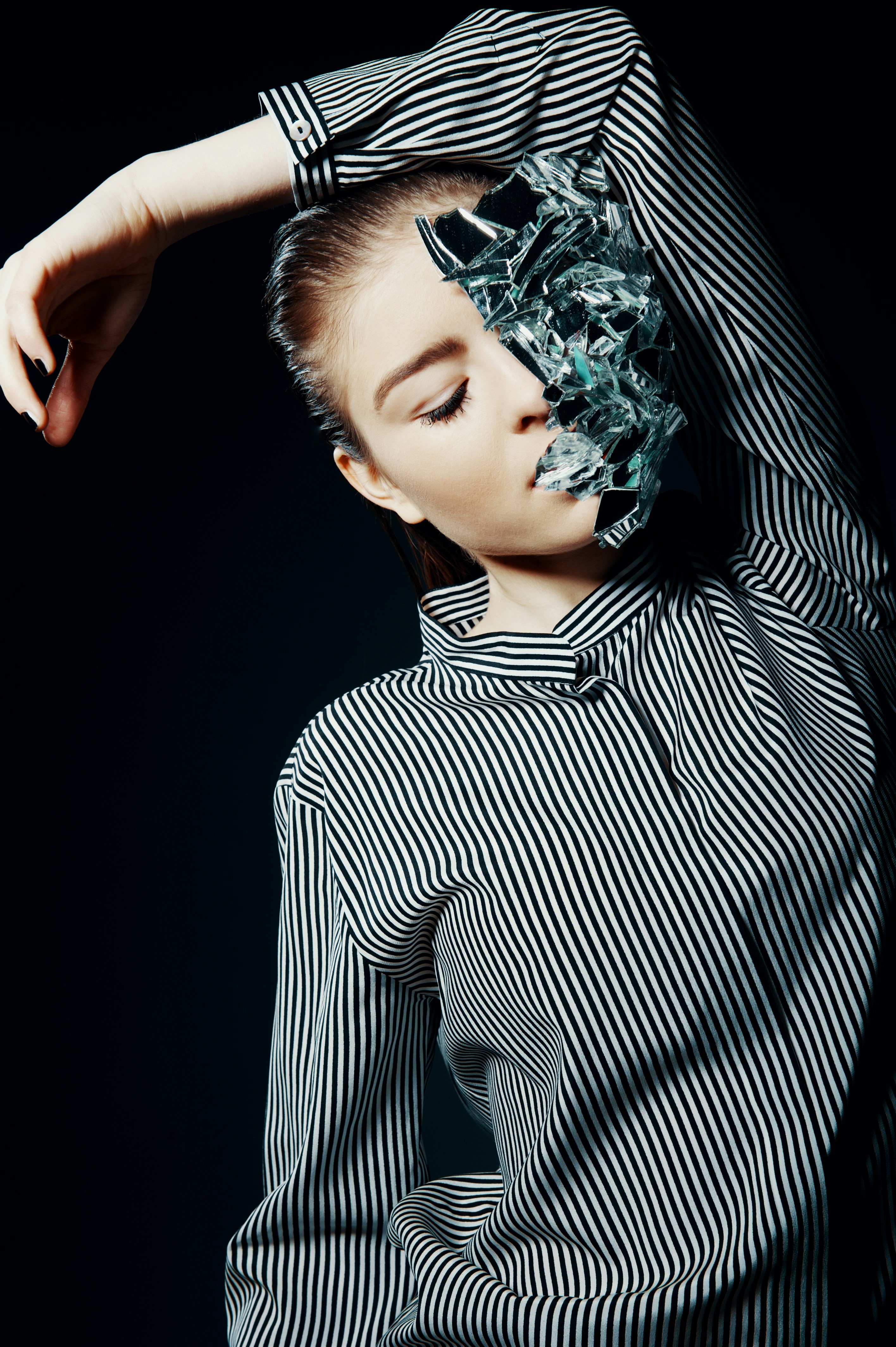 man in black and white striped dress shirt holding his head