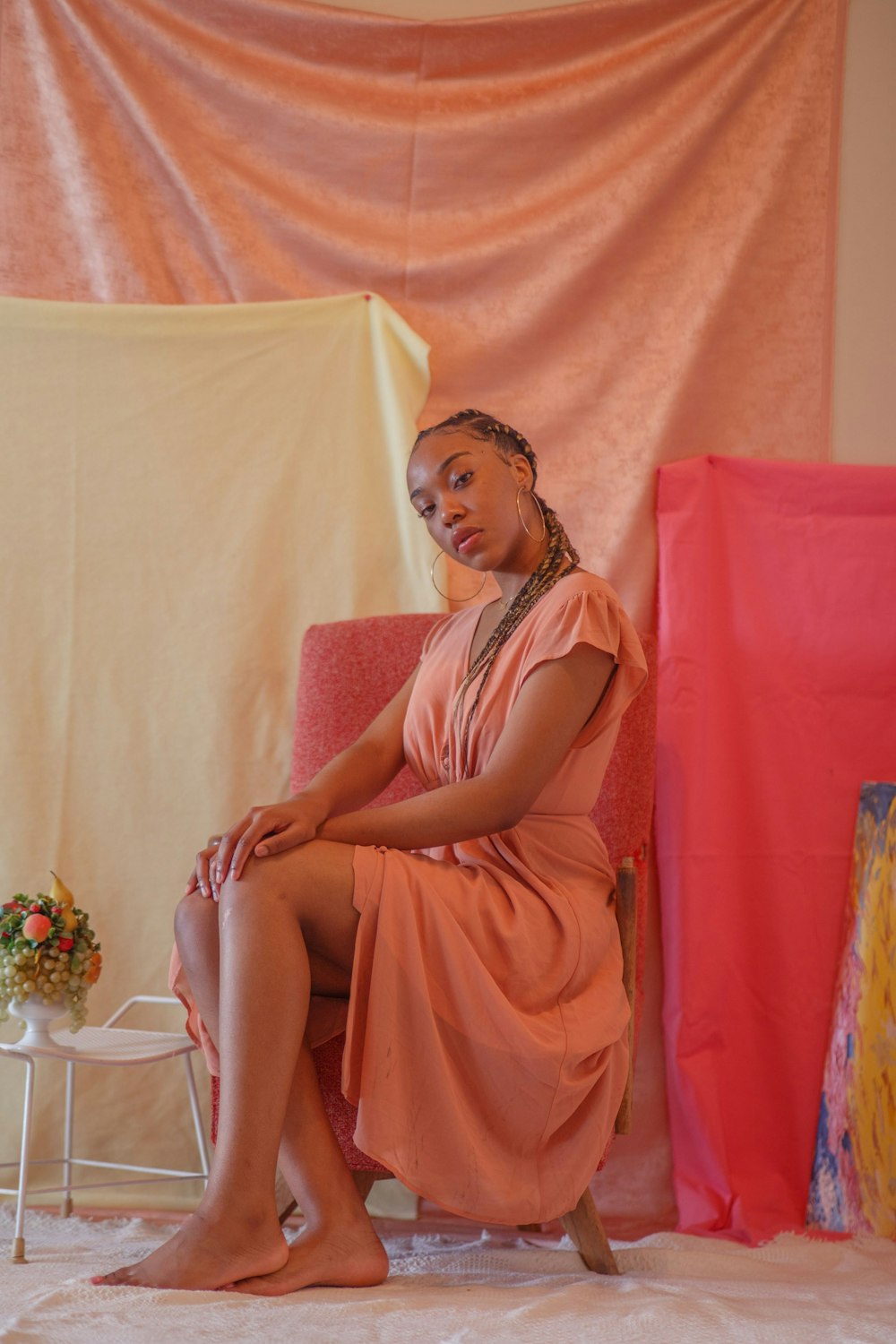 woman in orange sleeveless dress sitting on pink couch