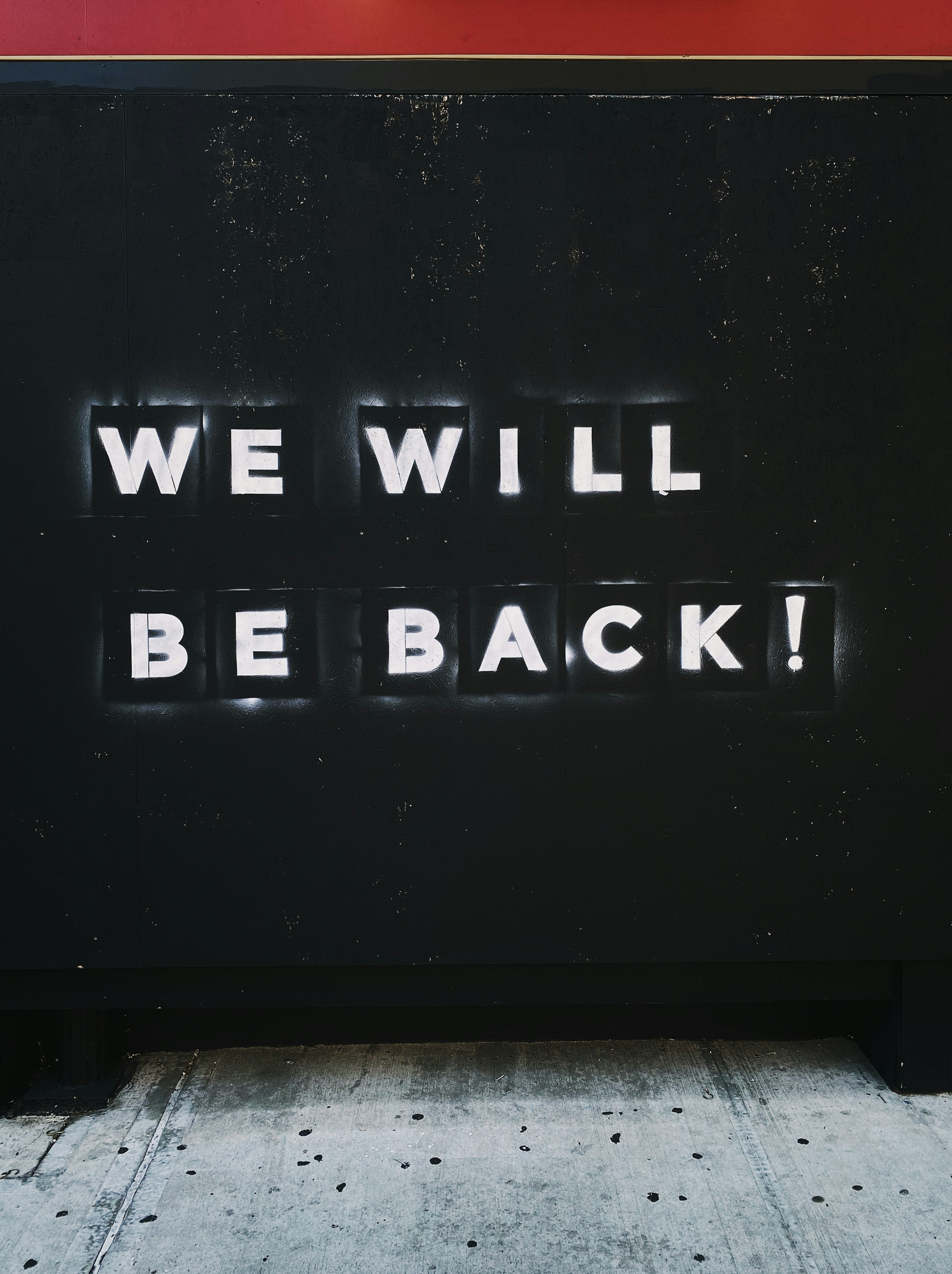 a sign that says we will be back on the side of a building