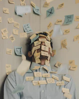 man covered in sticky notes at office desk