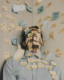 man covered in sticky notes at office desk
