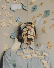 stressad man som står vid väggen med en massa post-it lappar över och runt sig