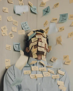 man covered in sticky notes at office desk