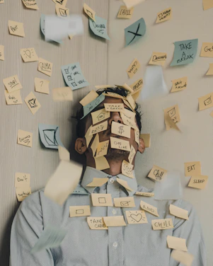 man covered in sticky notes at office desk