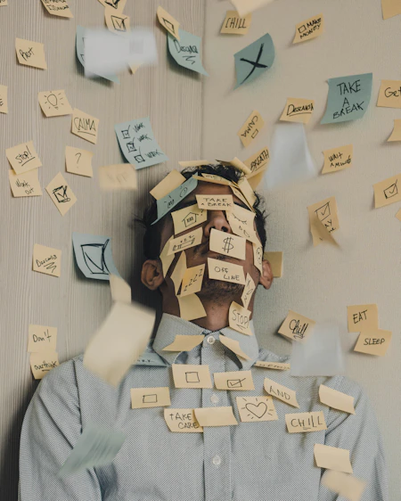 man covered in sticky notes at office desk