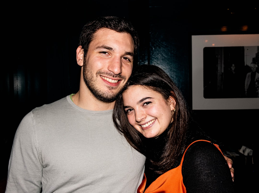 man in gray crew neck shirt beside woman in orange shirt