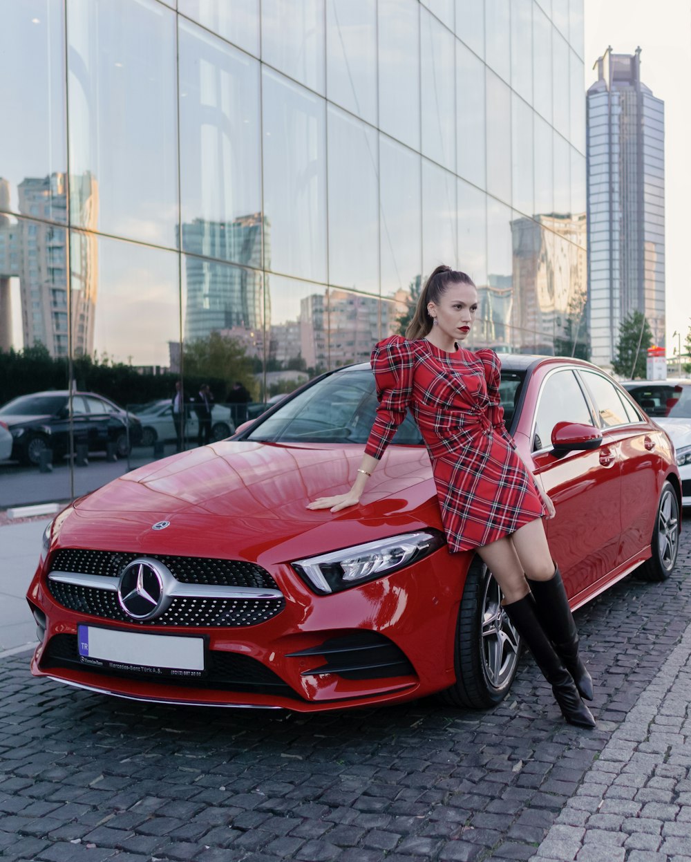 woman in red and black plaid dress shirt standing beside red mercedes benz car