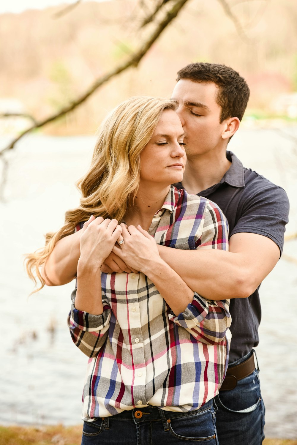 man in blue crew neck t-shirt kissing woman in plaid shirt