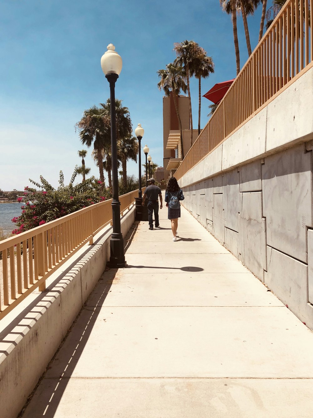 man in black jacket and black pants walking on sidewalk during daytime