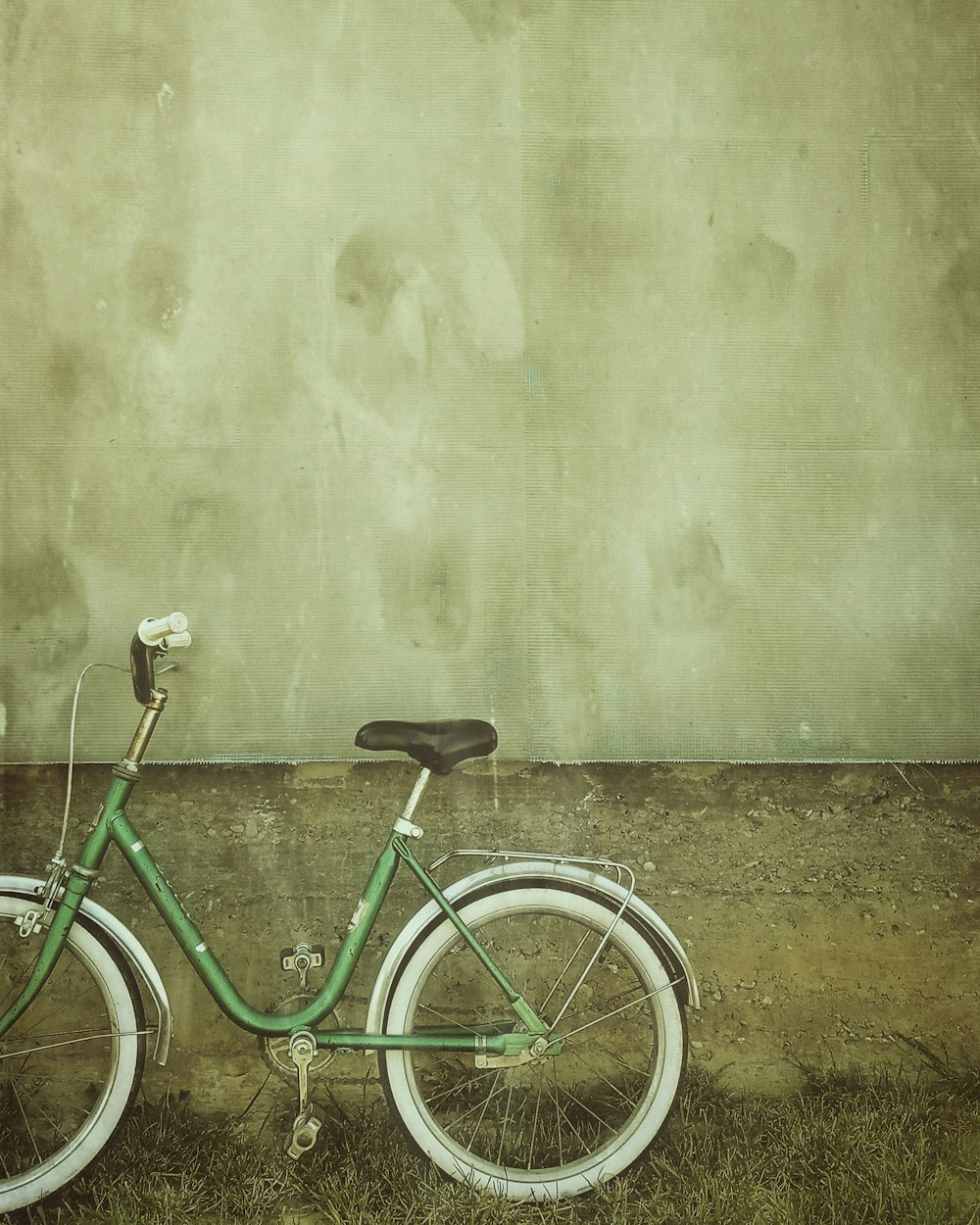 green city bicycle leaning on wall