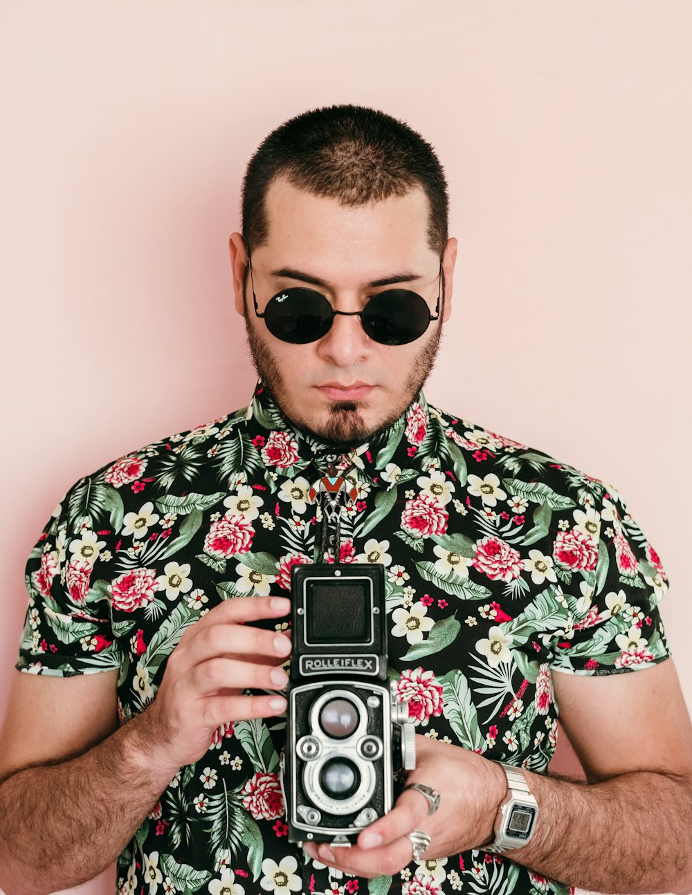 man in white red and green floral button up shirt holding black and silver camera