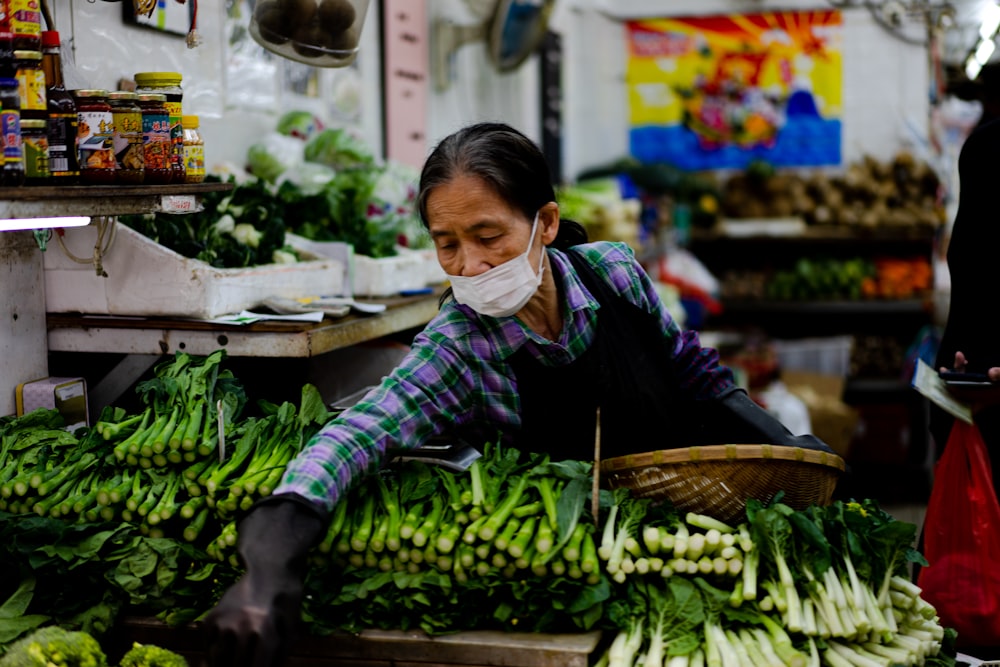 緑の野菜を持つ黒いジャケットの女性