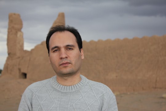 man in gray crew neck shirt standing on brown field during daytime in Kashan Iran