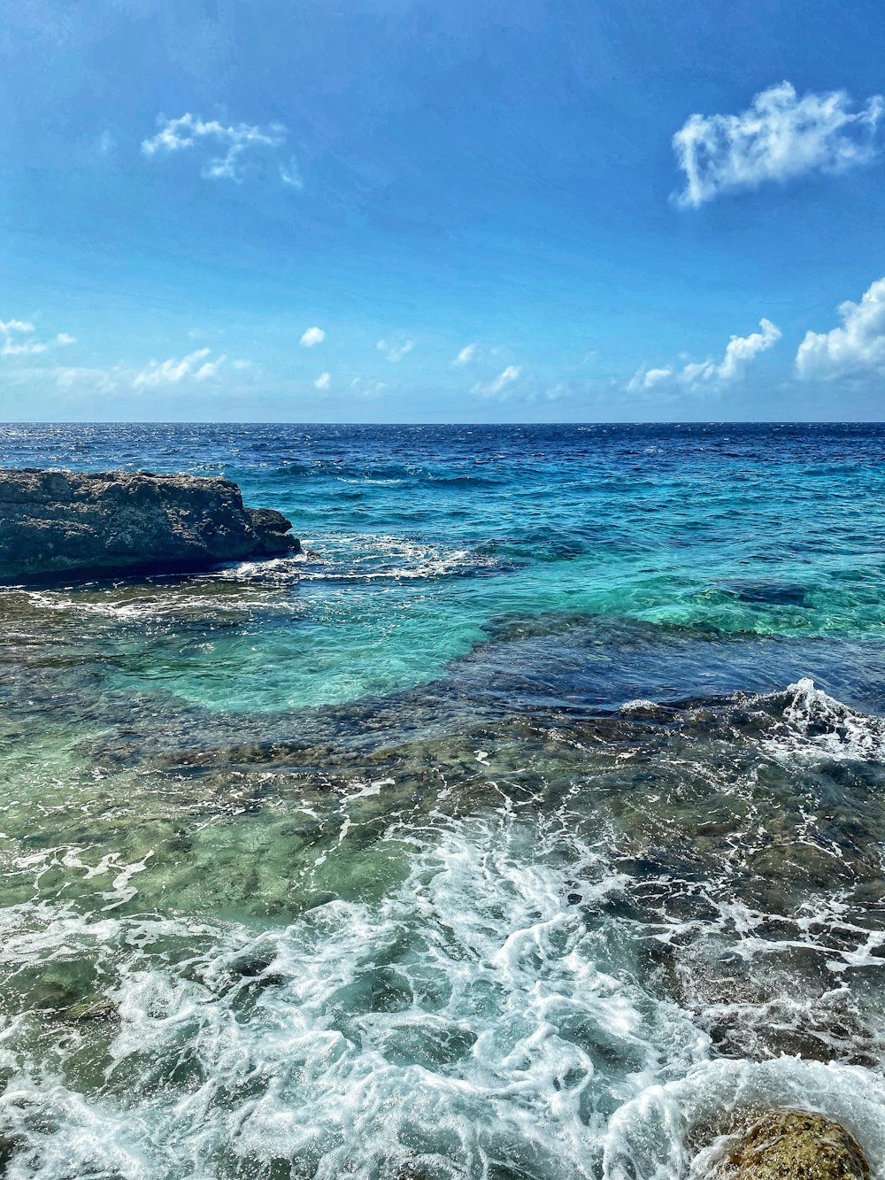 昼間の青空の下の海に浮かぶ茶色の岩層