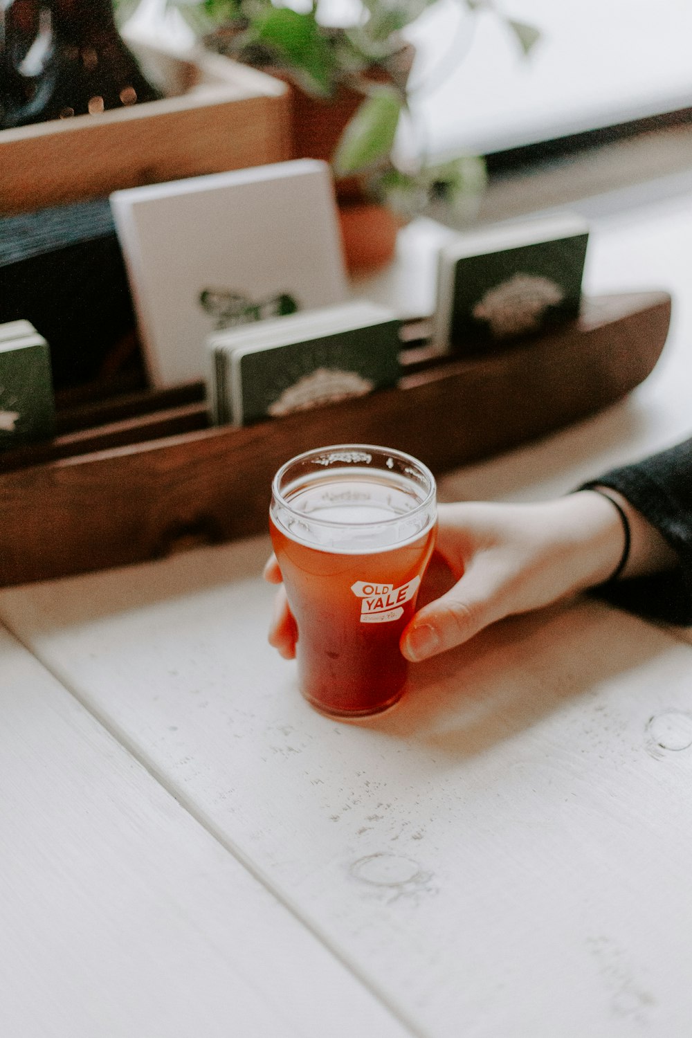 person holding clear drinking glass with red liquid