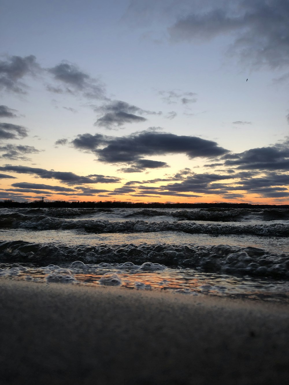 sea waves crashing on shore during sunset