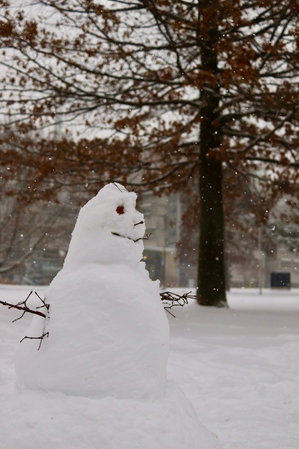 snowman covered with snow near bare trees during daytime