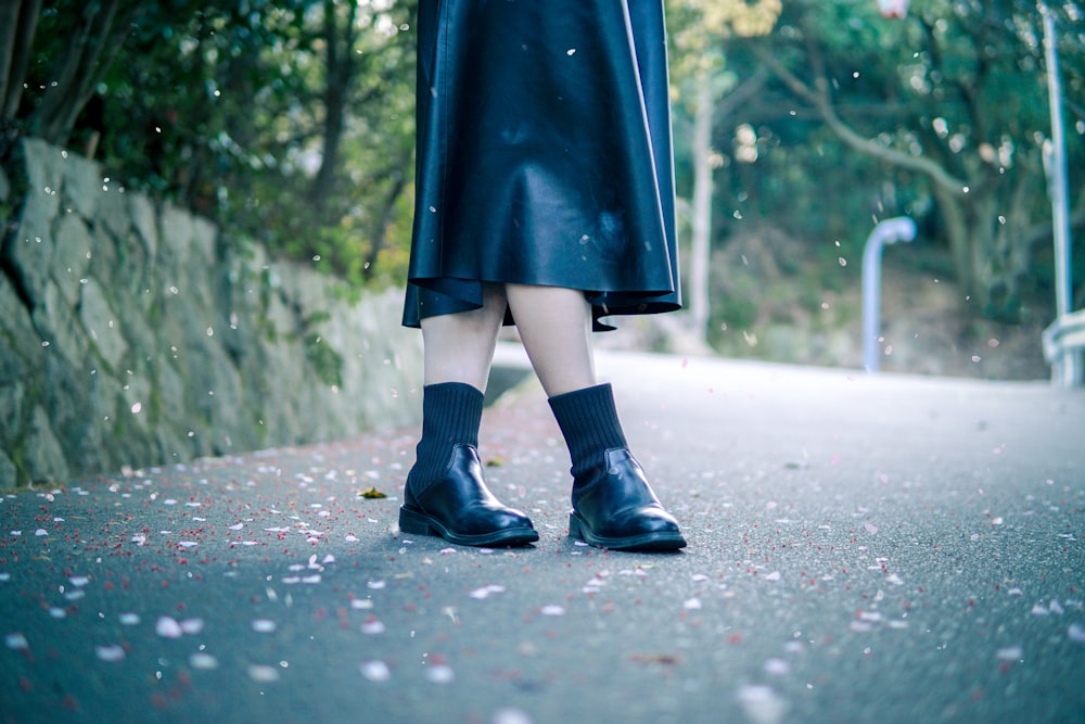 person in black rain boots walking on road during daytime