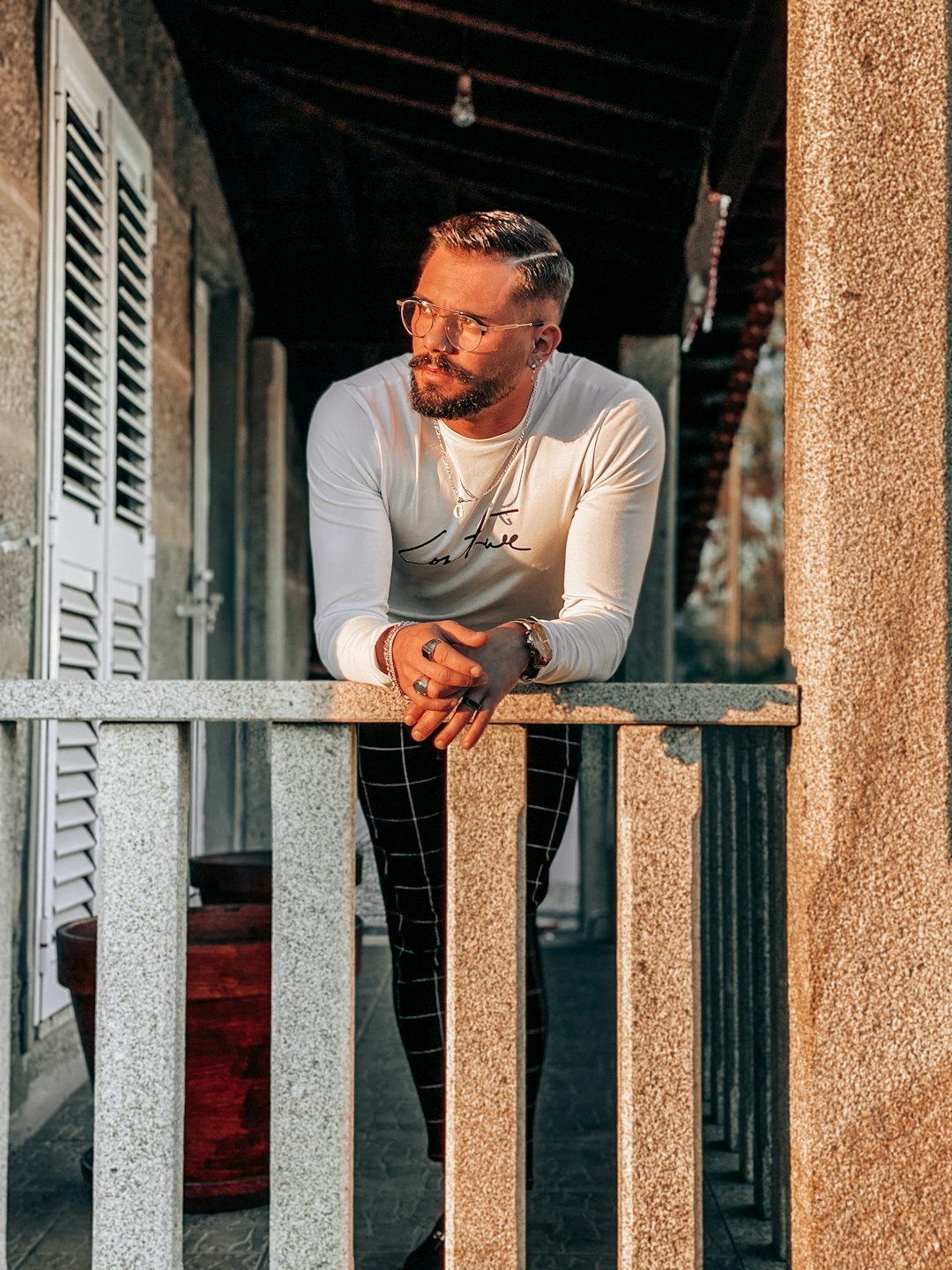 man in white long sleeve shirt and black pants standing beside brown concrete wall during daytime