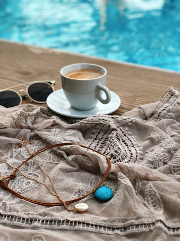 A serene lifestyle shot of a woman wearing subtle, modern jewelry while enjoying a quiet morning coffee.